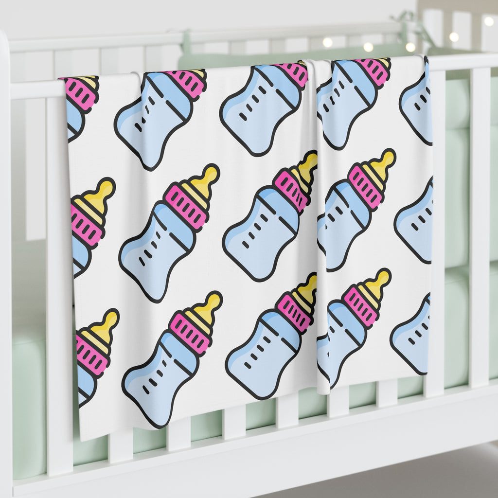 Baby blanket with bottle pattern draped over a crib