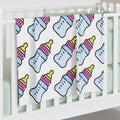Baby blanket with bottle pattern draped over a crib