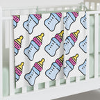 Baby blanket with bottle pattern draped over a crib