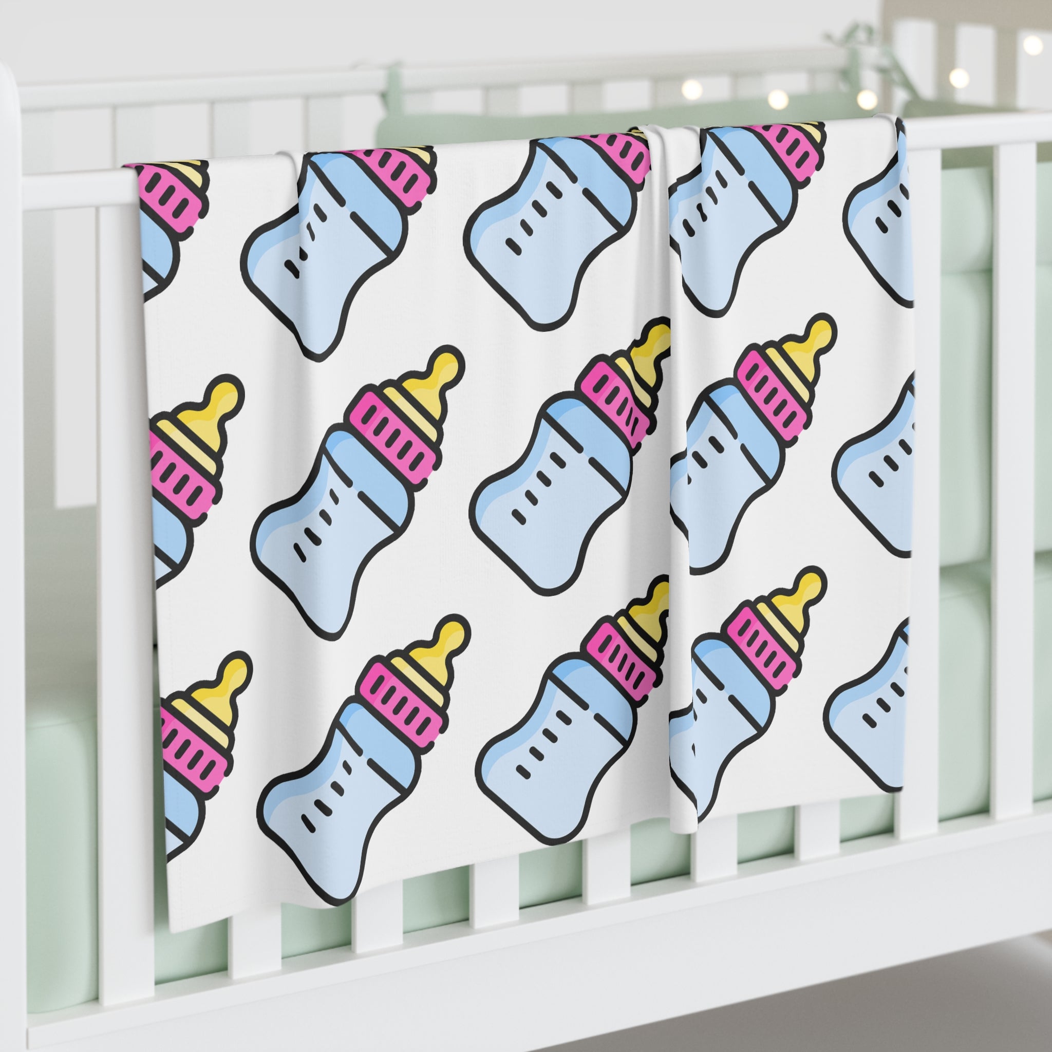 Baby blanket with bottle pattern draped over a crib