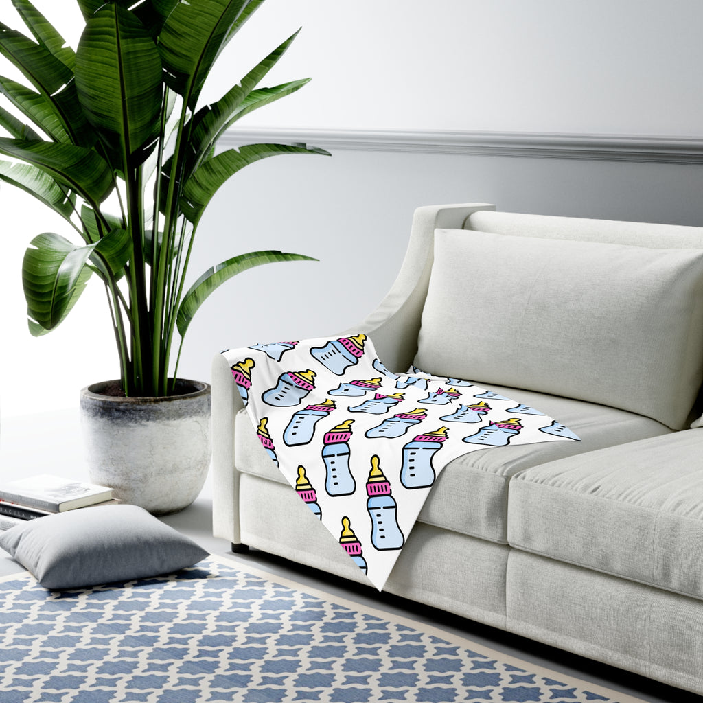 Decorative blanket with bottle pattern on a gray sofa in a living room setting.
