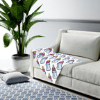Decorative blanket with bottle pattern on a gray sofa in a living room setting.